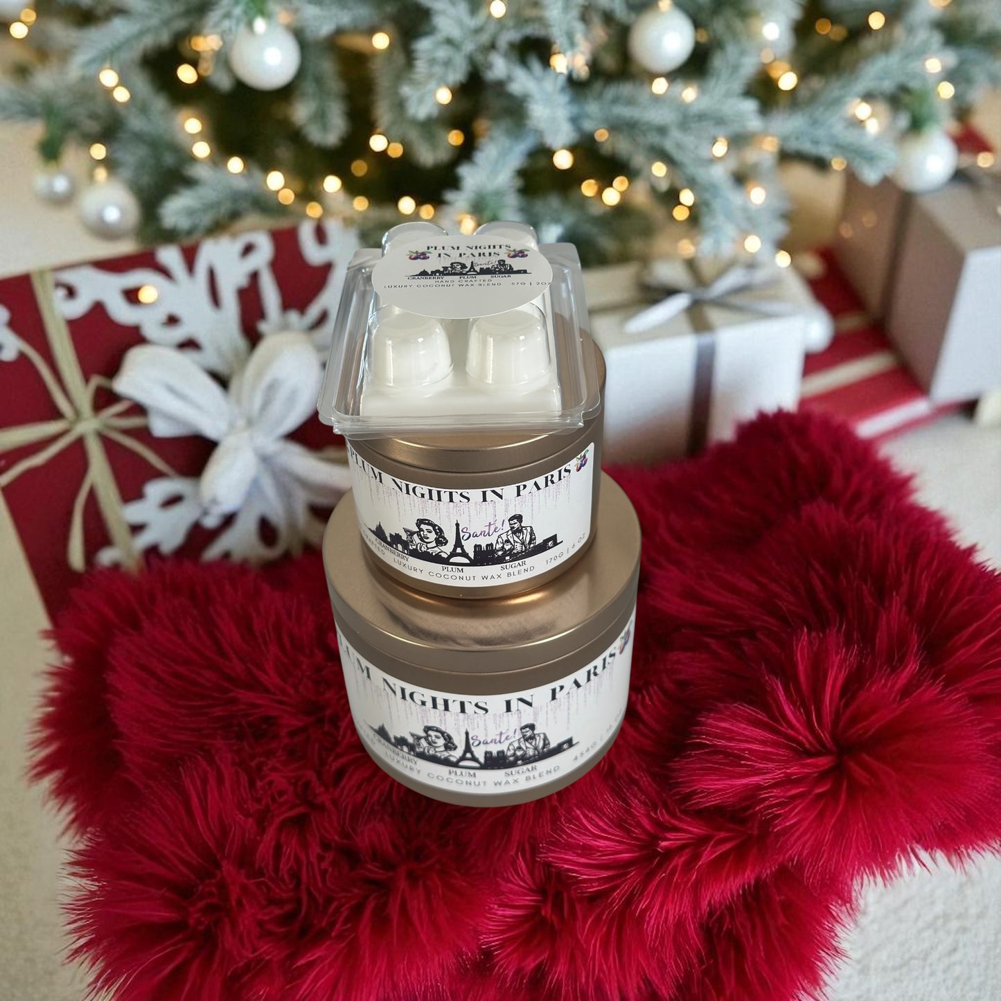 A Christmas collection of gold candle tins and white wax melts labeled "Plum Nights in Paris" resting on a red fluffy rug with Christmas presents and a decorated Christmas tree in the background.
