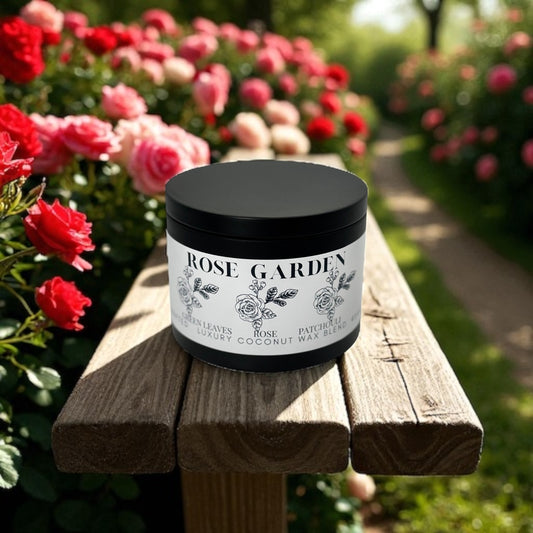 Black candle tin  labeled 'Rose Garden' on a wooden bench with roses in the background