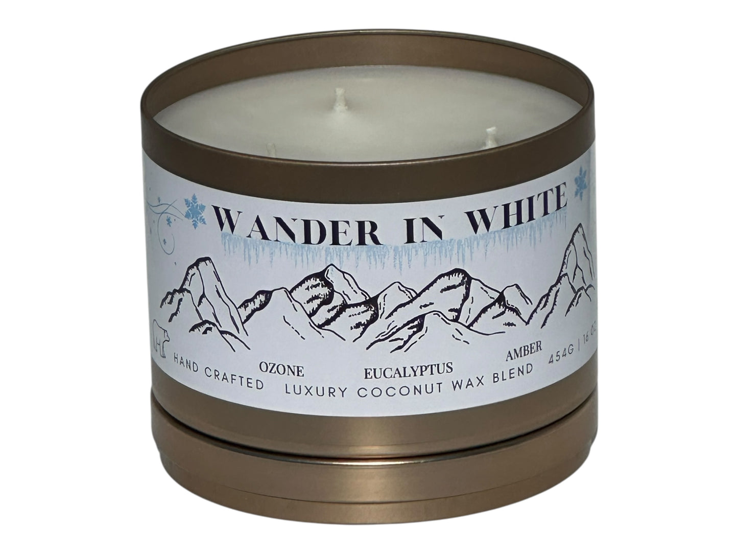 Candle in a gold tin with a mountain-themed labeled "Wander in White" on a white background
