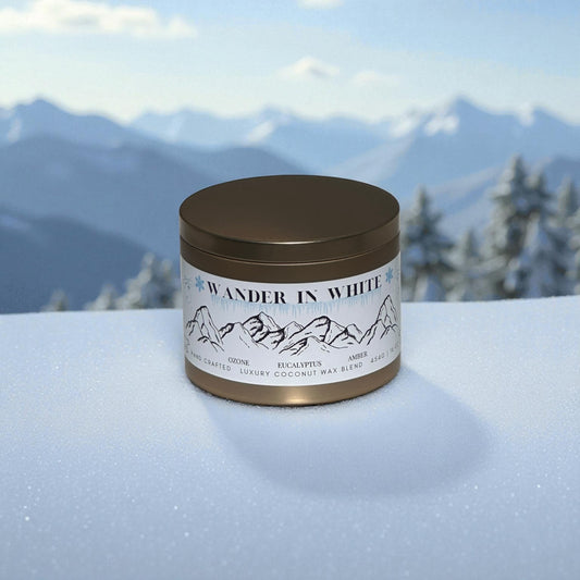 Candle jar labeled 'Wander in White' on a snowy surface with mountains in the background