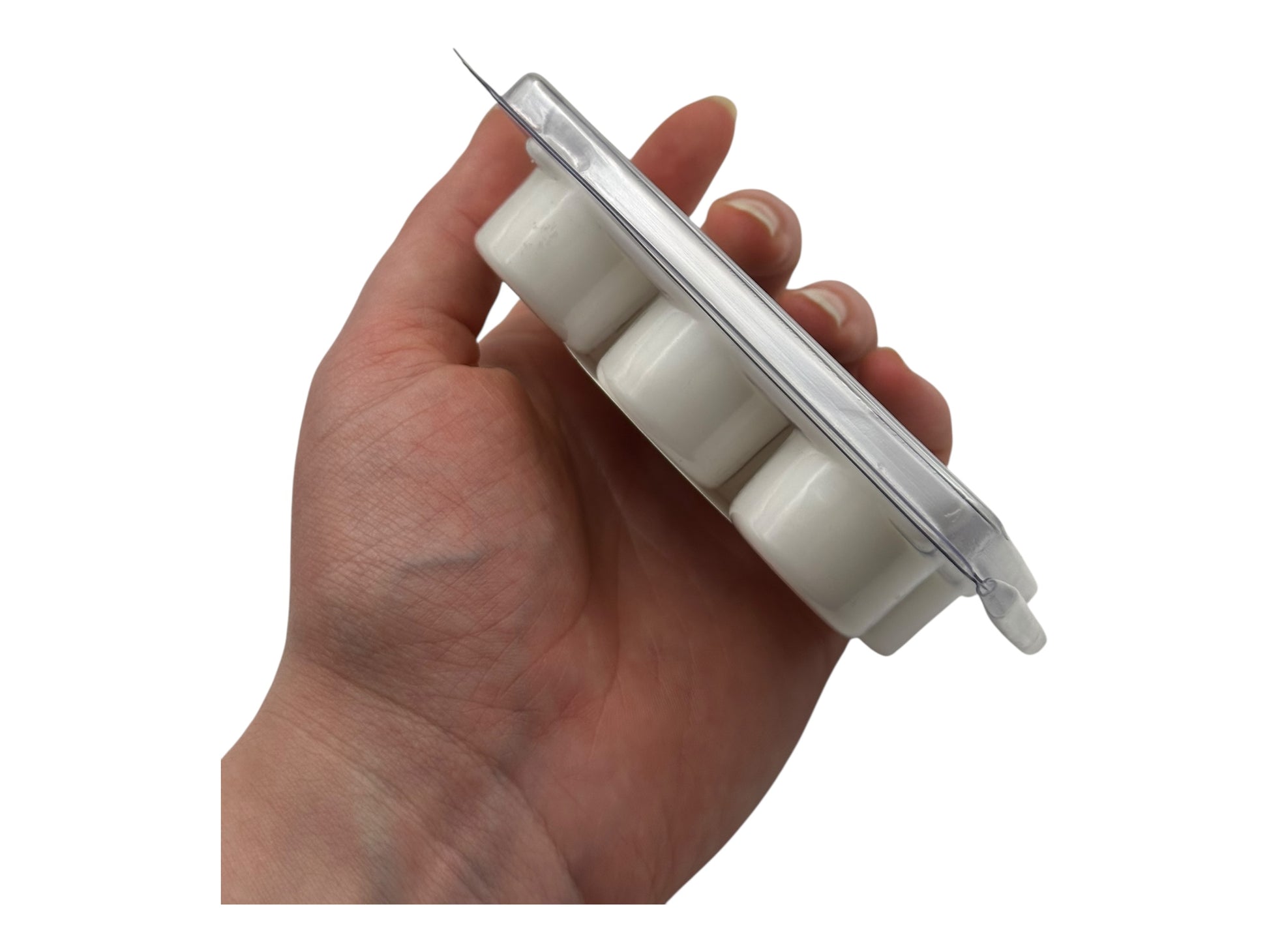 A hand holding white wax melt on a white background.